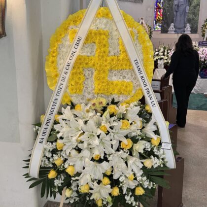 Peaceful Buddhist Symbol – Double Layer Spray featuring yellow and white chrysanthemums, lilies, and roses on a stand.