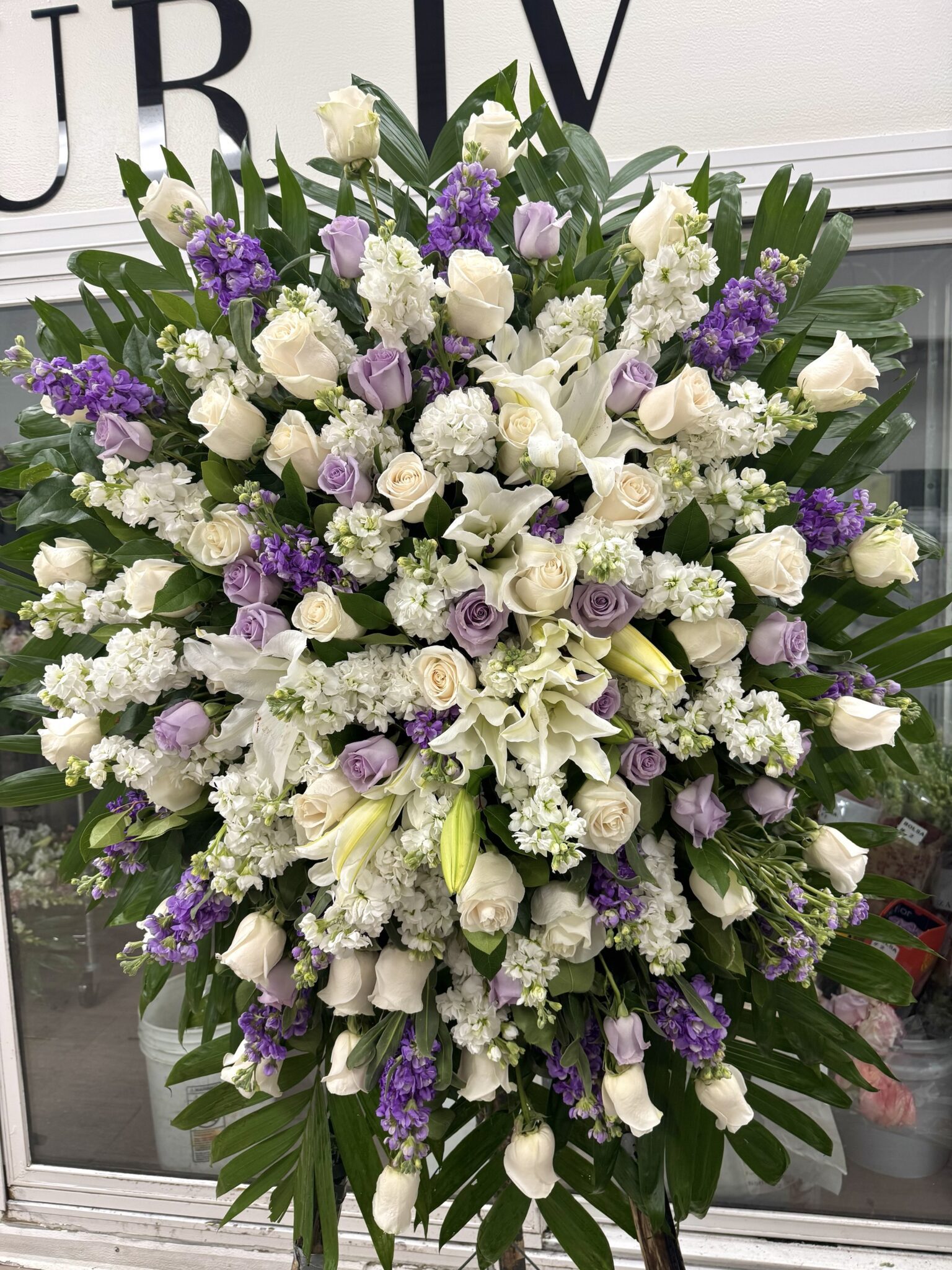 Silver Lining Funeral Spray - Elegant Floral Tribute featuring white roses, lilies, and lavender stock flowers.