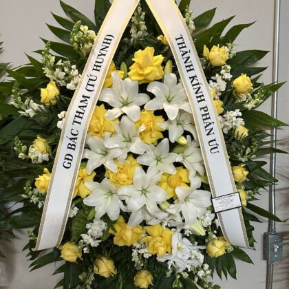 Moonlit Memories – Graceful Funeral Spray featuring white lilies and yellow roses with lush greenery on a stand.