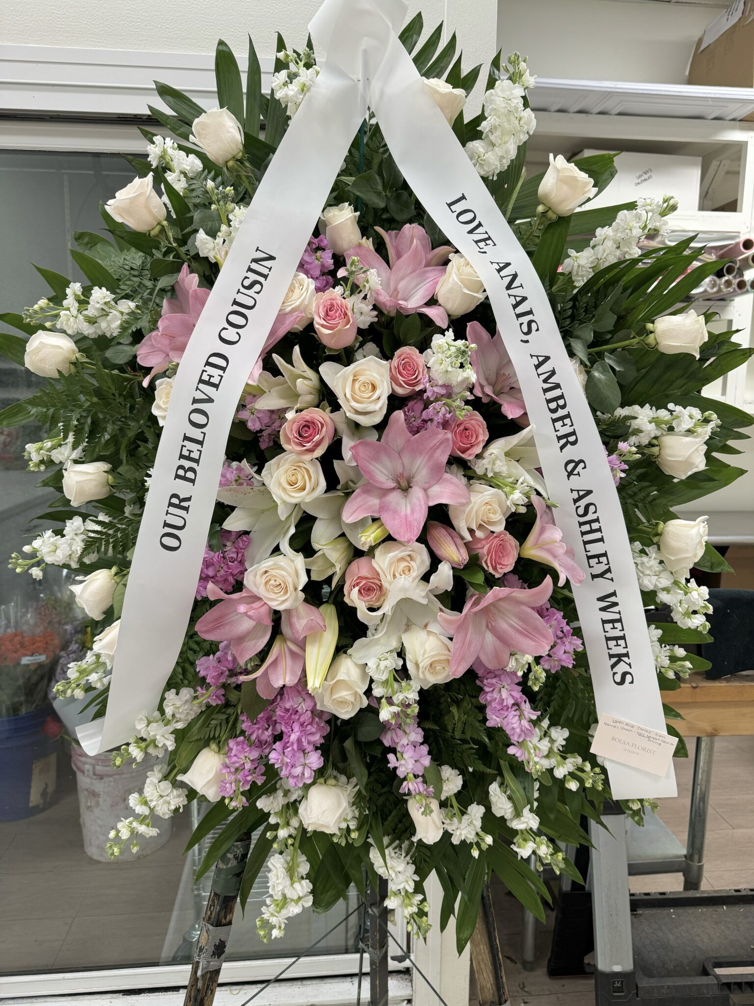 Sunbeam Sympathy – Elegant Funeral Spray featuring white roses, pink lilies, and lavender stock flowers on a stand.