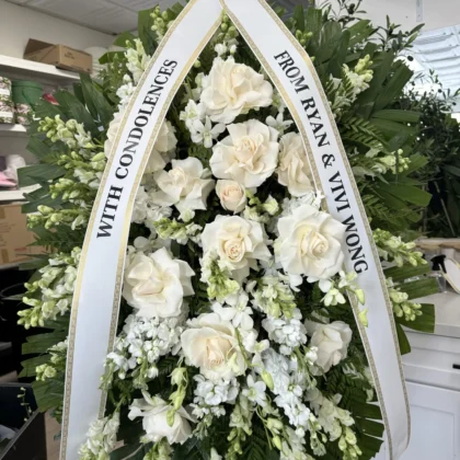 Winter Essence Funeral Spray - Classic Elegance featuring white roses and snapdragons with a personalized condolence ribbon.