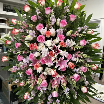 Rosie Remembrance Funeral Spray - Vibrant Tribute featuring pink and white roses, lilies, and lush greenery.