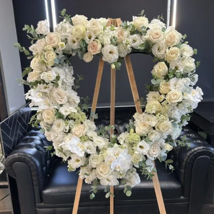 Warm Embrace Funeral Spray, a heart-shaped Loving Embrace Funeral Spray featuring white roses and orchids for a tribute.