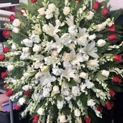 Whispering Willows Funeral Spray - Elegant Tribute featuring white lilies, roses, and red roses in a lush arrangement.