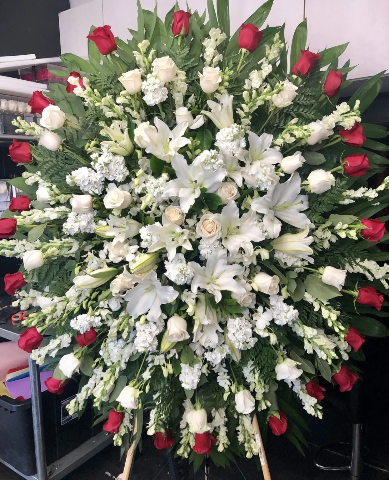 Whispering Willows Funeral Spray - Elegant Tribute featuring white lilies, roses, and red roses in a lush arrangement.