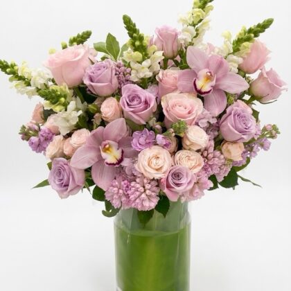 Eden Sauvage – Majestic Floral Vase featuring soft pink and lavender roses, orchids, and snapdragons in a glass vase.