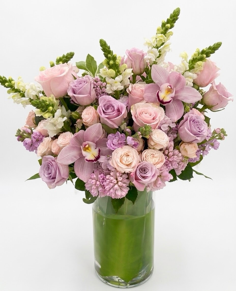 Eden Sauvage – Majestic Floral Vase featuring soft pink and lavender roses, orchids, and snapdragons in a glass vase.