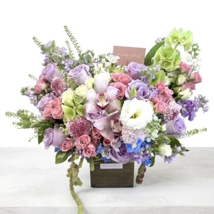 A luxurious arrangement of pastel roses, orchids, and delicate blooms in soft purples and pinks.