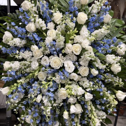 A luxurious floral arrangement featuring white roses and delicate blue delphiniums, elegantly cascading.