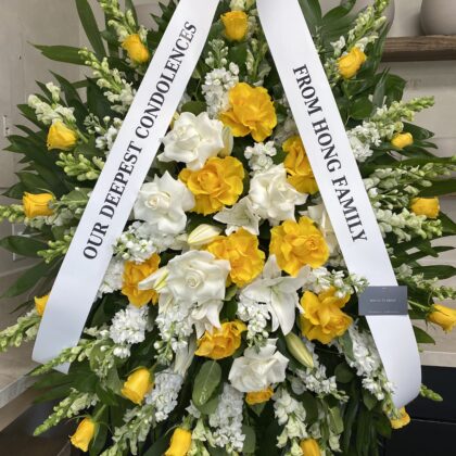 Elegant Soft Farewells Funeral Spray featuring yellow roses, white lilies, and snapdragons with a condolence ribbon.