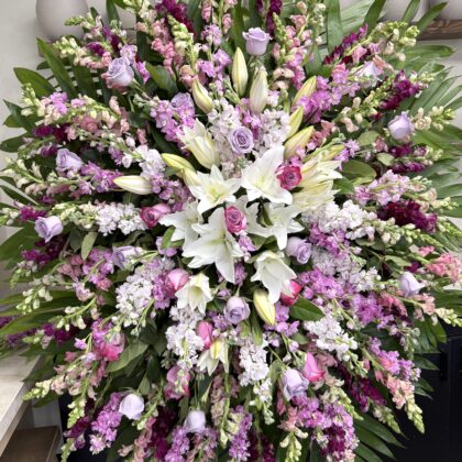 Gentle Blooms Funeral Spray for Lasting Tribute featuring lavender roses, white lilies, and purple snapdragons.