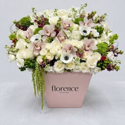 A lush arrangement of white roses, pale pink orchids, and anemones in a pink Florence Flowershop box.