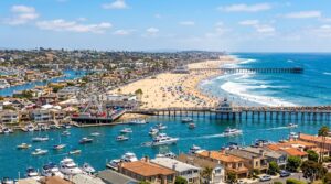 Aerial view of Newport Beach, CA, featuring a bustling harbor, sandy beach, and pier for Flower Delivery in Newport Beach.