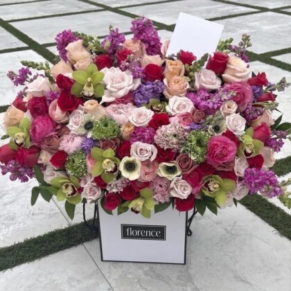 A luxurious Florence floral arrangement featuring vibrant roses, orchids, and stock in shades of pink, red, and green.