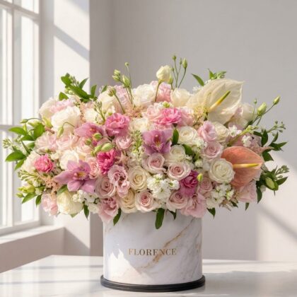 A luxurious floral arrangement of pink and white roses, orchids, and anthuriums in a marble-patterned Florence box.